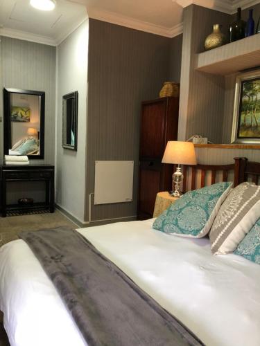 a bedroom with a large white bed and a mirror at Rabbit Hole Hotel in Krugersdorp