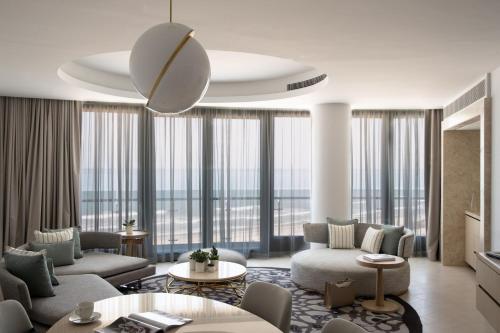 a living room with couches and tables and windows at Jumeirah Saadiyat Island Abu Dhabi in Abu Dhabi
