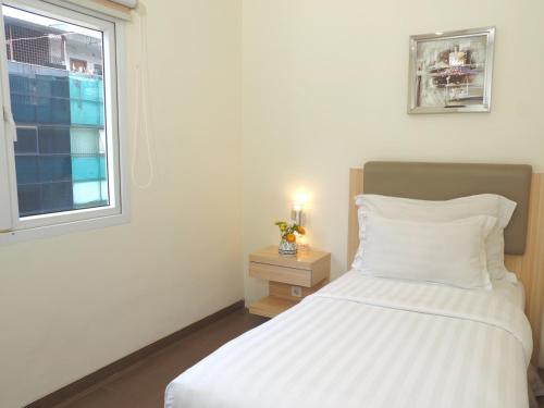 a bedroom with a white bed and a window at d'primahotel WTC Mangga Dua in Jakarta