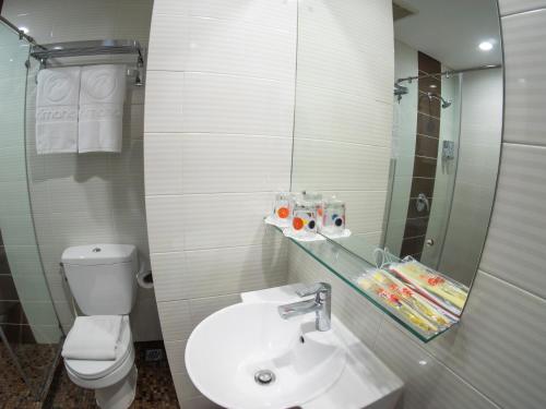 a bathroom with a toilet and a sink and a mirror at d'primahotel WTC Mangga Dua in Jakarta