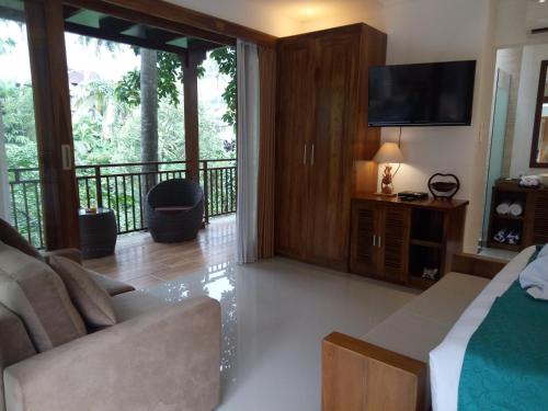 a room with a bed and a television and a balcony at The Pesaren Ubud in Ubud