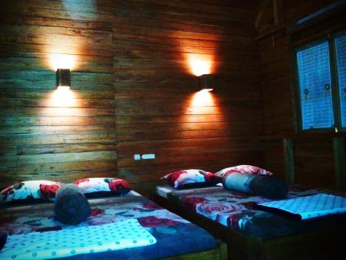 two beds in a room with wooden walls and lights at NAYYLA Homestay in Pangandaran