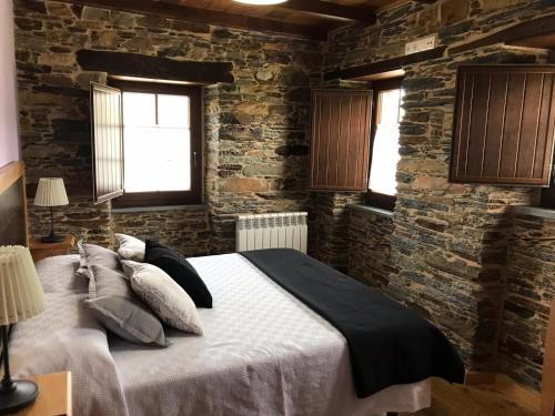 San Tirso de AbresにあるApartamentos Carolaのレンガの壁に大きなベッドが備わるベッドルーム1室が備わります。