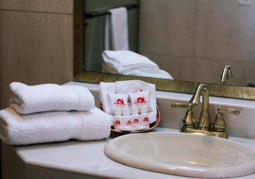 een badkamer met handdoeken, een wastafel en een spiegel bij Mi Pueblo Samary Hotel Boutique in Sucre