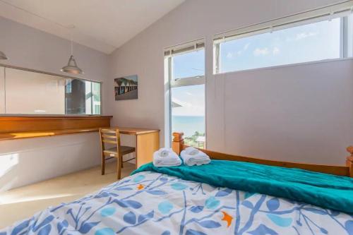 a bedroom with a bed and a desk and a window at Exclusive Sanctuary on the West Coast in Muriwai Beach