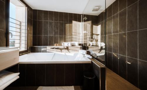 a bathroom with a large tub and a sink at Citta di Lume Suites & Lofts in Porto-Vecchio