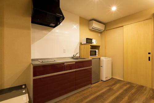 a small kitchen with a sink and a refrigerator at Guesthouse Raku in Kyoto