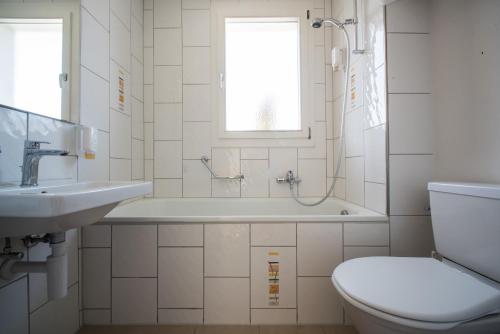 een badkamer met een bad, een toilet en een wastafel bij Jungfrau Hotel in Wilderswil