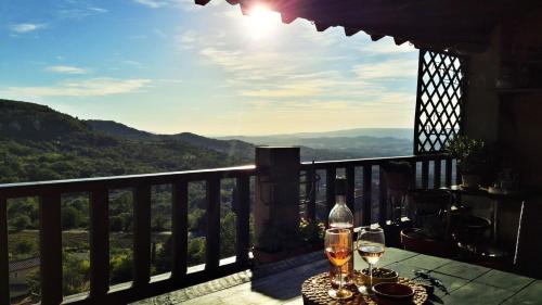a table with wine glasses on a balcony with a view at Entre Terre et Ciel. in Saignon