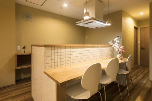 a kitchen with a counter with two chairs and a table at Guesthouse Raku in Kyoto