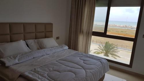 a bedroom with a bed with a view of the beach at RESIDENCE PUERTO MARINA Corniche d'Asilah in Asilah