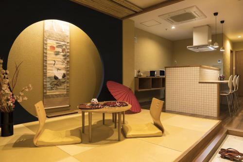 a living room with a table and chairs and a kitchen at Guesthouse Raku in Kyoto