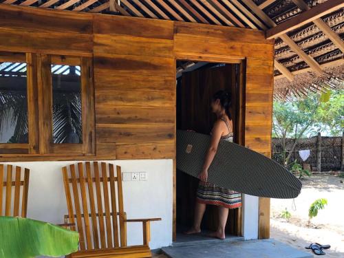 a woman is holding a surfboard in a building at Kadjan villa in Arugam Bay