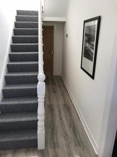 a hallway with stairs with a picture on the wall at Glens of Antrim Beach House - On the Coast in Glenariff