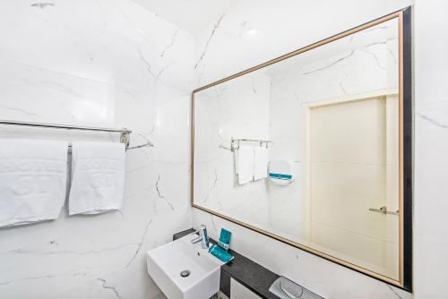 Baño blanco con lavabo y espejo en Hotel 81 Osaka en Singapur