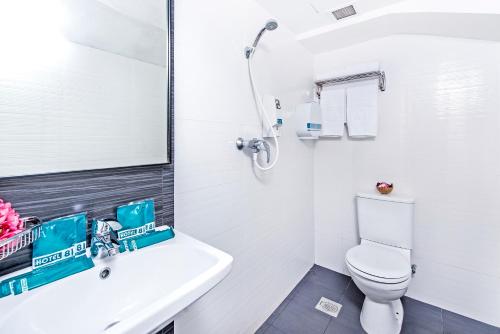 a white bathroom with a toilet and a sink at Hotel 81 Selegie in Singapore