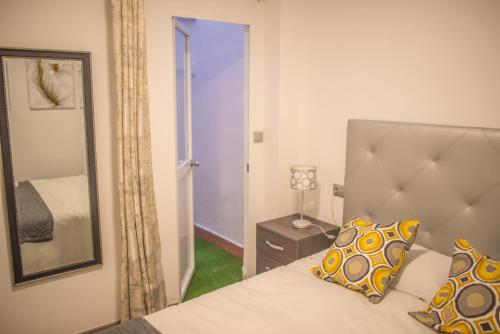 een slaapkamer met een bed, een spiegel en een deur bij Apartamento Padilla Playa Huelin in Málaga