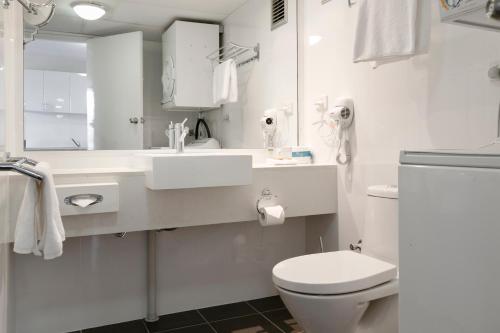 a white bathroom with a toilet and a sink at Summit Apartments in Brisbane