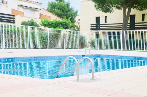 - une piscine à côté d'une clôture blanche dans l'établissement Appartement Cap Estivales, au Cap d'Agde