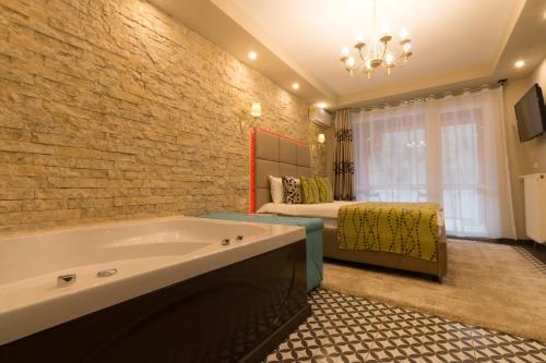 a large bathroom with a tub and a bed at Romantic Jacuzzi Belleview Studio in Sinaia