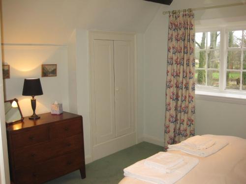 a bedroom with a bed and a dresser and a window at Job's Mill Cottage in Warminster