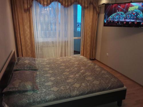 ein Schlafzimmer mit einem Bett mit einem großen Fenster in der Unterkunft Элитная Люкс квартира с видом на реку Иртыш! in Pawlodar