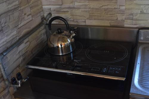 a tea kettle sitting on top of a stove at Shoei backpackes hostel in Teshikaga