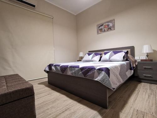 um quarto com uma cama grande com lençóis roxos e brancos em West House Apartments-Mar Mikhael em Beirute