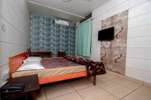 1 dormitorio con 1 cama y TV. en National Guest House en Jalandhar