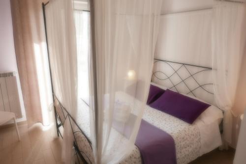 sypialnia z łóżkiem z fioletową pościelą i oknem w obiekcie B&B Ai Tre Archi w mieście Spotorno