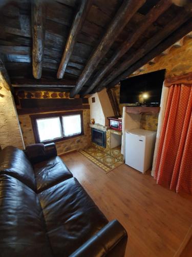 a living room with a leather couch and a fireplace at El Bú in Peralejos de las Truchas