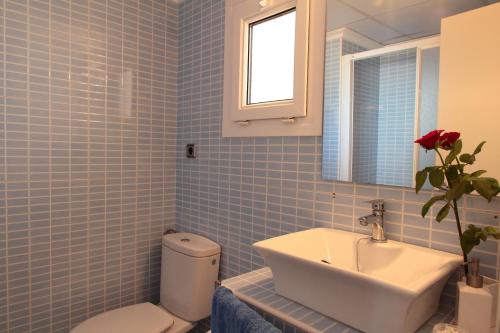 a blue tiled bathroom with a sink and a toilet at Canyamel 27 in Canyamel