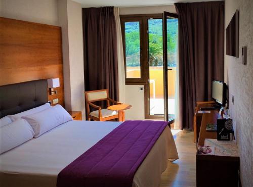 a hotel room with a large bed and a television at Hotel Balneario Valle del Jerte in Valdastillas