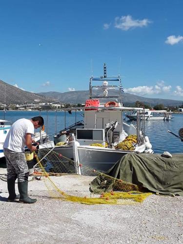 a man standing next to a boat in the water at me gusta suite by the sea in Anavissos