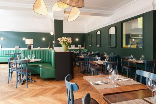 un restaurante con paredes verdes, mesas y sillas en The Originals Boutique, Hôtel Ô Gayot, Bagnoles-de-l'Orne (Inter-Hotel), en Bagnoles de l'Orne