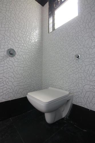a white toilet in a bathroom with a window at Hotel Apex in Navi Mumbai