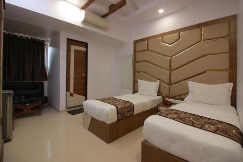 a hotel room with two beds and a television at Hotel Apex in Navi Mumbai