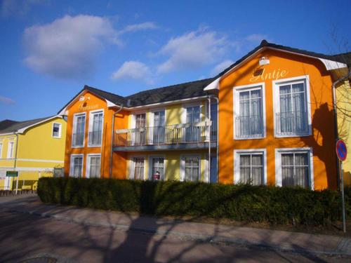 ein orangefarbenes Gebäude mit Balkon auf einer Straße in der Unterkunft Pension Haus Antje in Ahlbeck