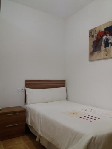 a bedroom with a white bed and a wooden nightstand at La casa del viajero in Ardales