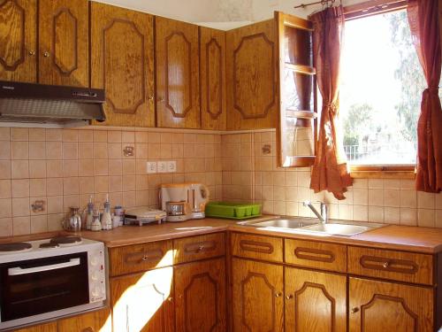a kitchen with wooden cabinets and a sink and a window at Elpidas Holiday House in Kardamyli