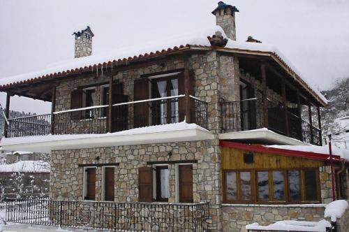 una casa de piedra con nieve encima en Ersis, en Neochori