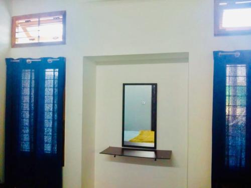 a mirror on a wall next to two windows at Bleu & Blanc in Puducherry