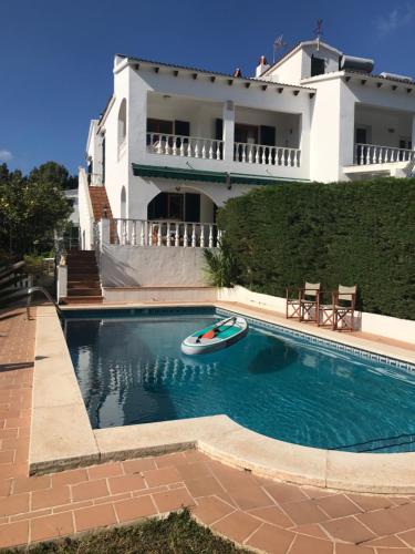 a house with a swimming pool with a boat in it at Casa 3 dormitorios Cala Galdana in Cala Galdana