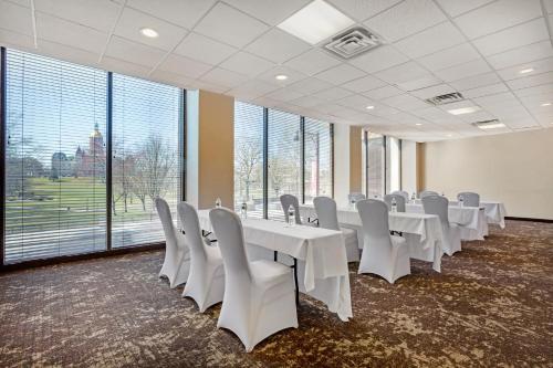 a conference room with white tables and chairs and large windows at The Capitol Hotel in Hartford