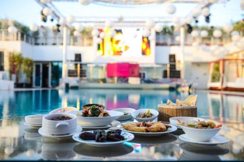 a table with plates of food next to a swimming pool at Sun City Hotel - The Gabriel in Cairo