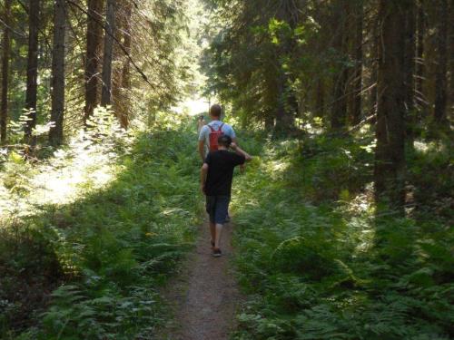 two people walking down a trail in the woods at KoliCarelia Cottages in Hattusaari