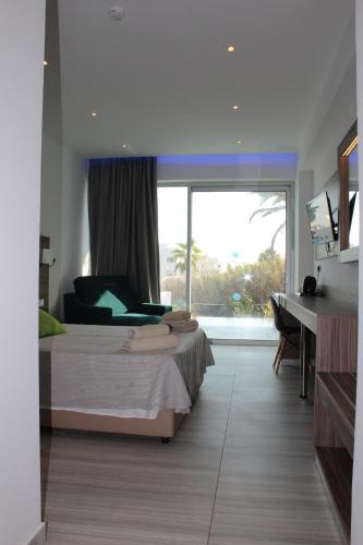 a bedroom with a bed and a desk and a window at Fedrania Gardens Hotel in Ayia Napa