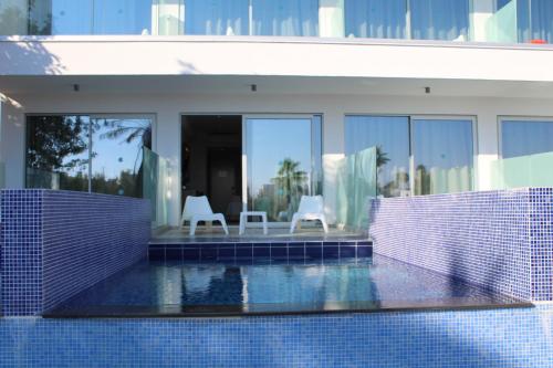 a house with a swimming pool with two chairs at Fedrania Gardens Hotel in Ayia Napa