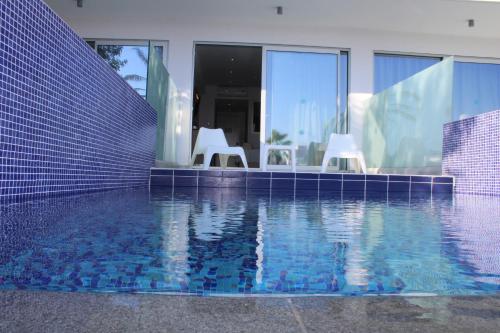 a swimming pool with two white chairs next to a house at Fedrania Gardens Hotel in Ayia Napa