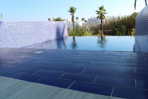 a swimming pool with blue tiles on the side of a building at Fedrania Gardens Hotel in Ayia Napa
